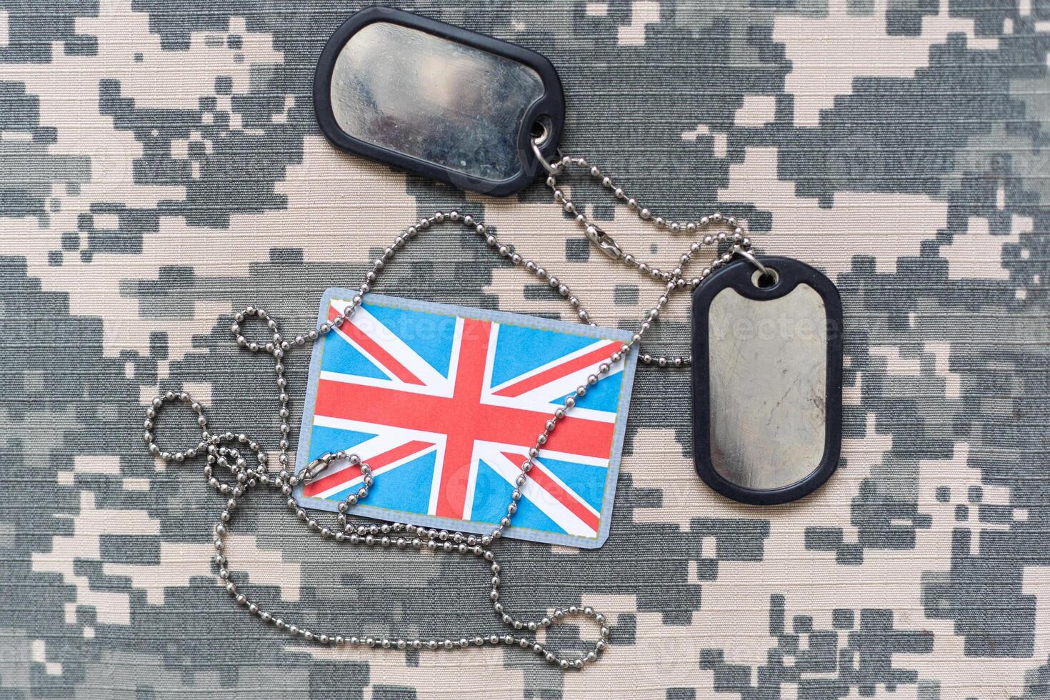 army blank, dog tag with flag of great britain on the khaki texture background. military concept photo