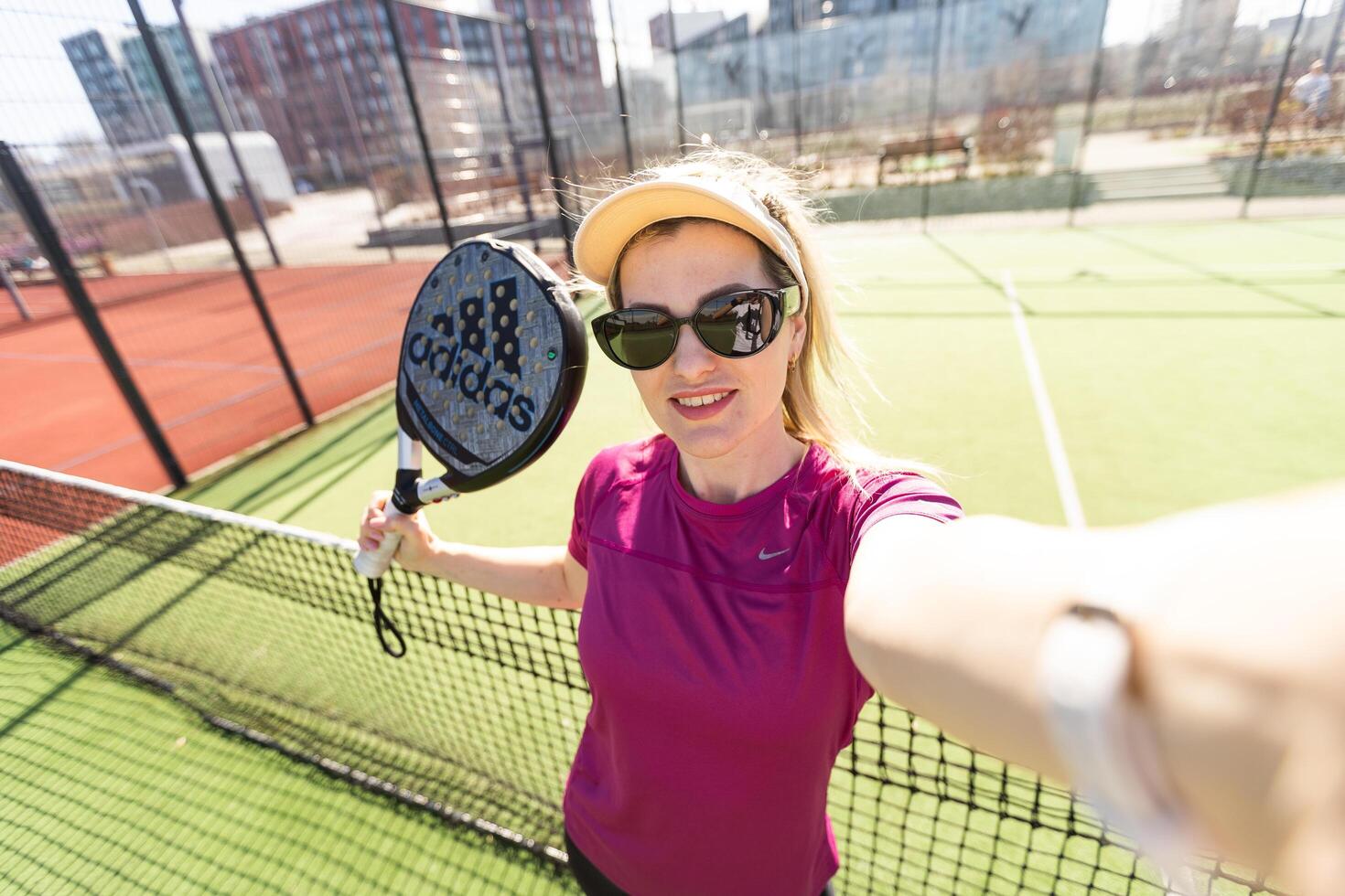 Ukraine Kyiv, March 31 2024. A girl in sportswear is training on a paddle tennis court. Concept of women playing paddle. photo