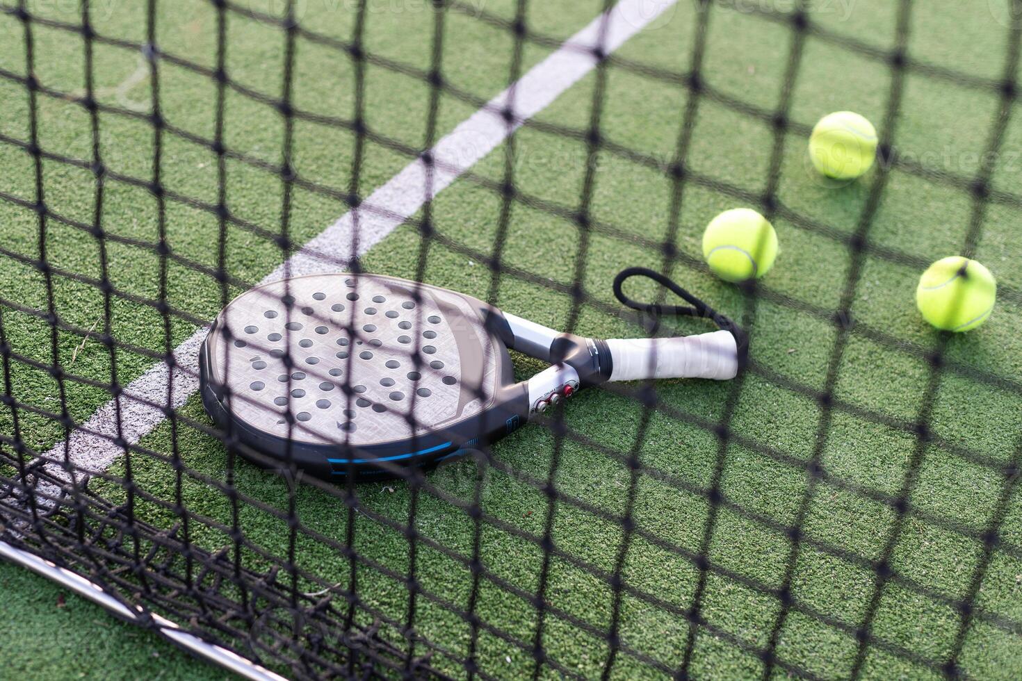 Paddle tennis racket, ball and net on the grass photo