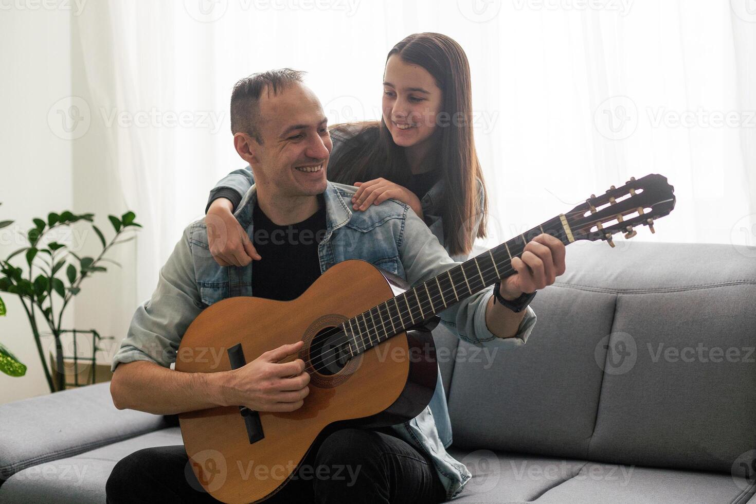 Father guy teaching girl teenager daughter guitar playing at home. Family musical lessons with strings instrument photo