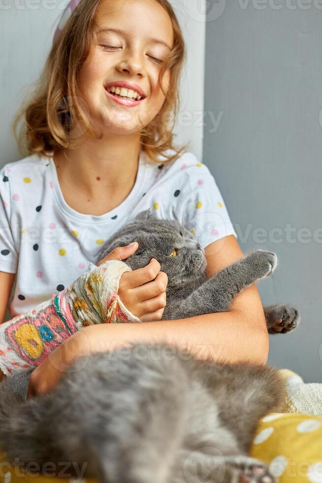 Teen girl with a broken arm orthopedic cast play with cat photo