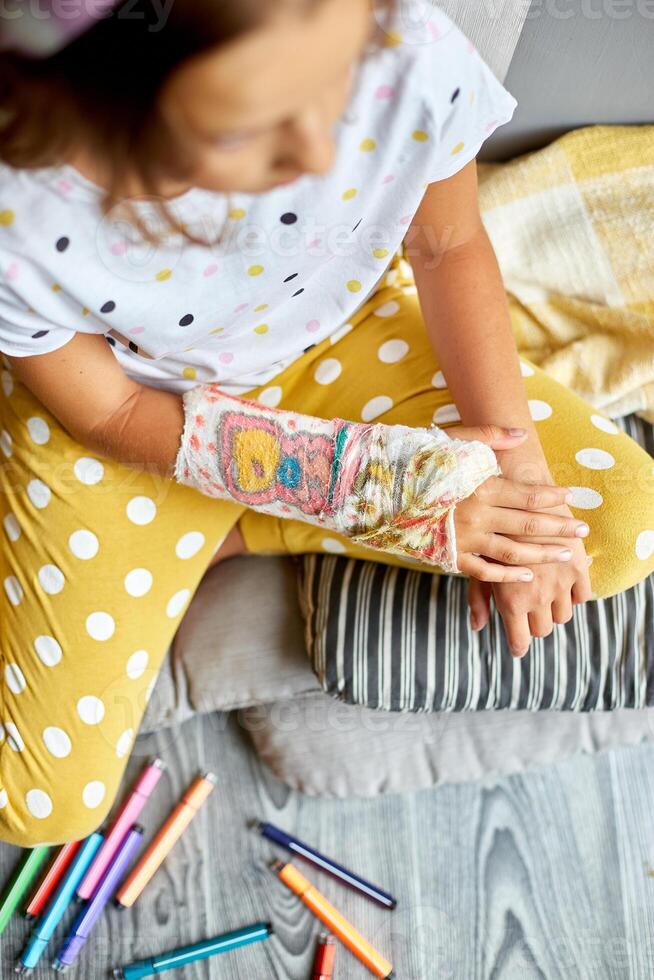 Teen girl with a broken arm at home an orthopedic cast photo