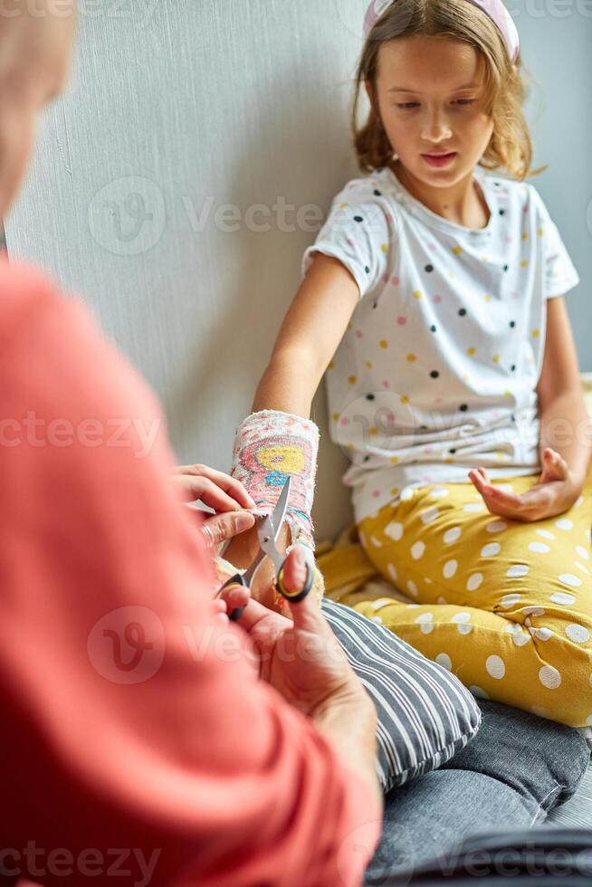 Father removing a plaster cast teen girl with a broken arm photo