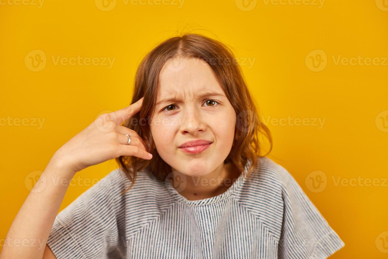 Teen girl portrait twists the finger near the temple photo