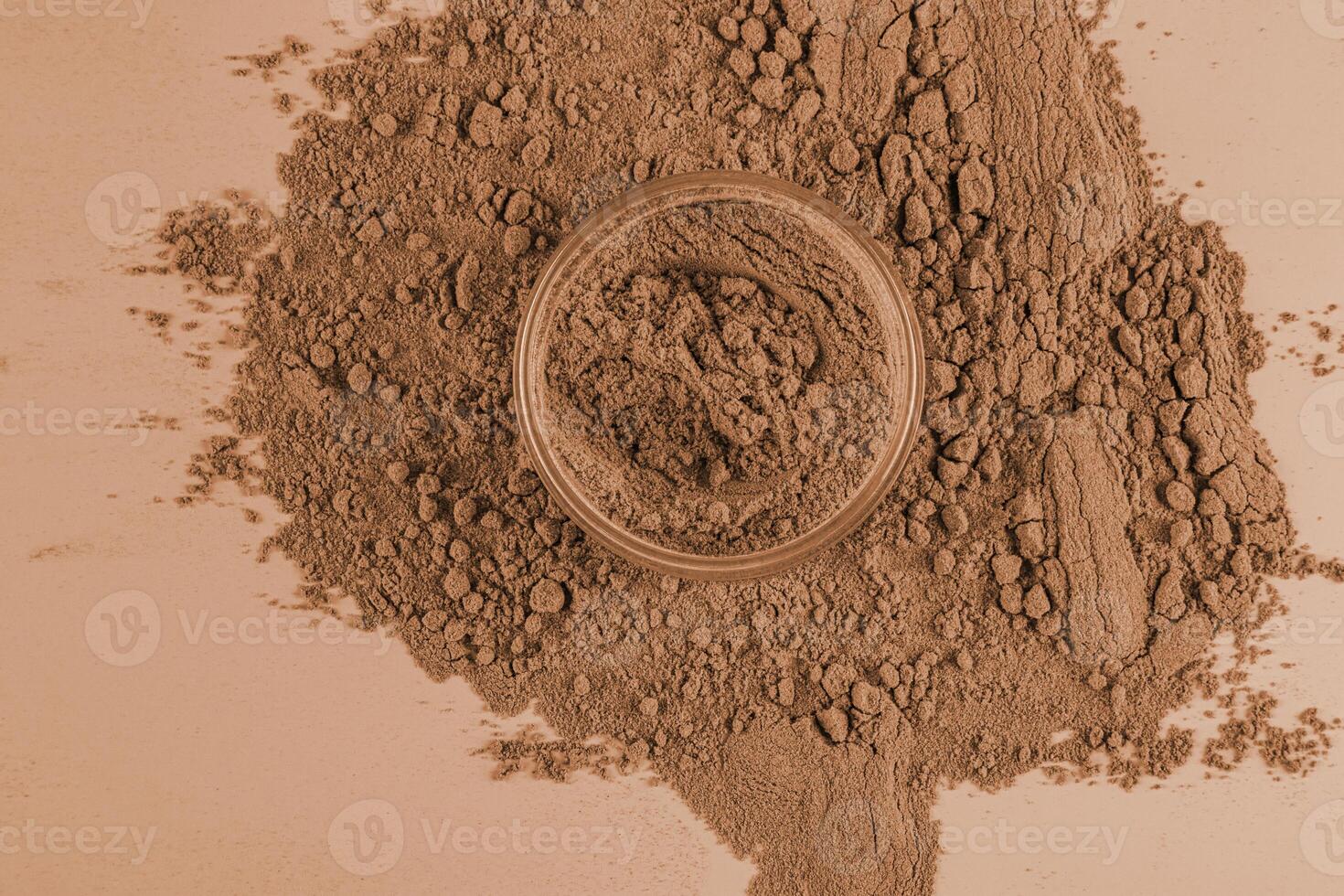 An open jar of loose powder in a bronze tone for dark skin on a background of a lot of loose texture . The concept of decorative cosmetics. photo