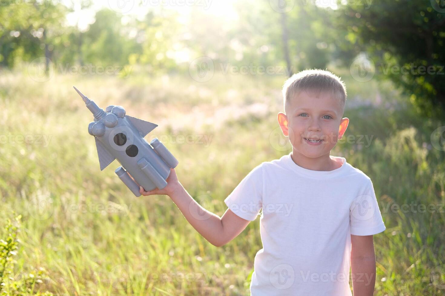 Little boy running with a toy rocket in a sunset field of summer nature. Children's big dream, flight, astronaut, space, success leader winner concept photo