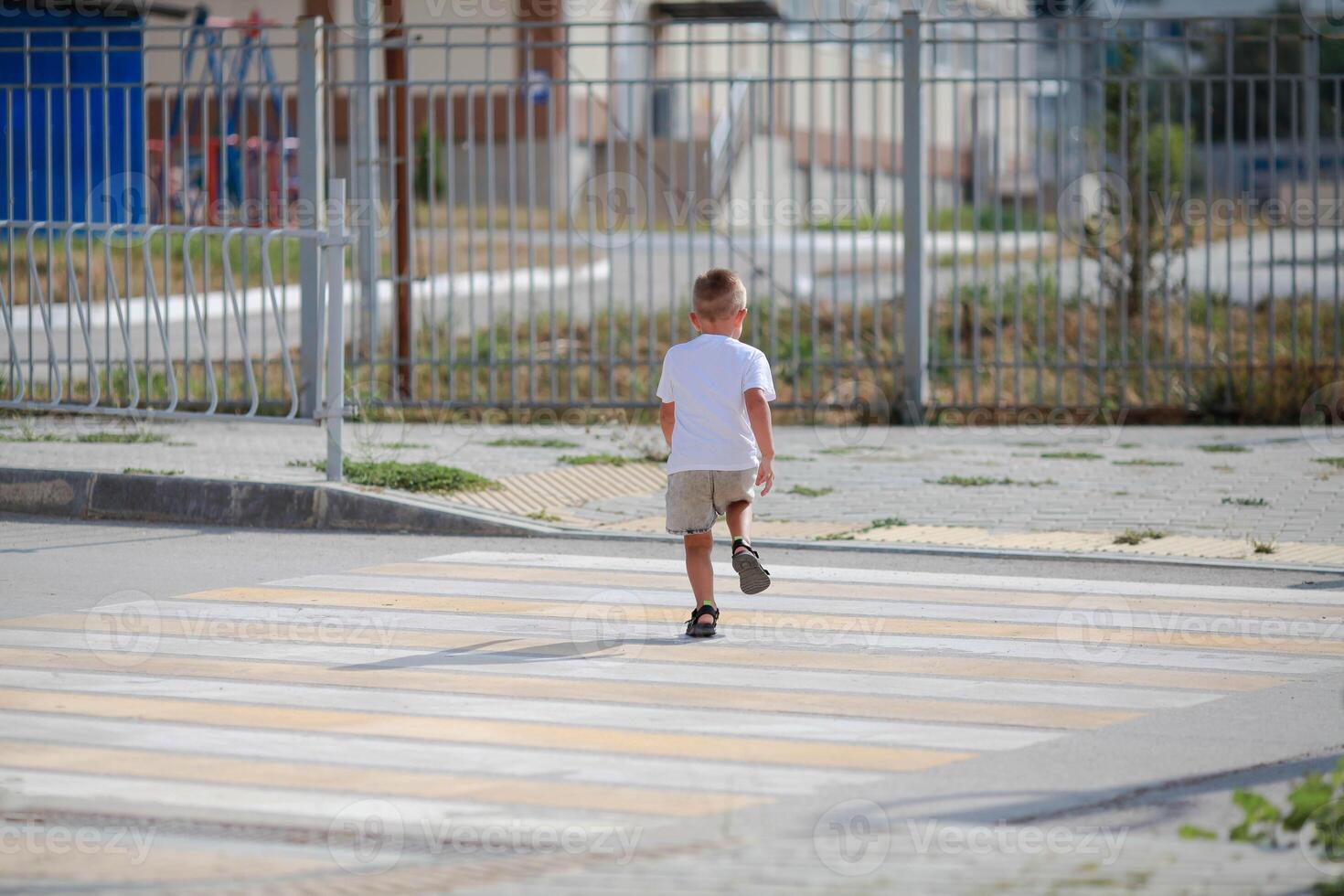 A little boy is running along the crosswalk. The child runs along the road to kindergarten and school. Zebra walking in the city. Concept of pedestrians passing crosswalk photo