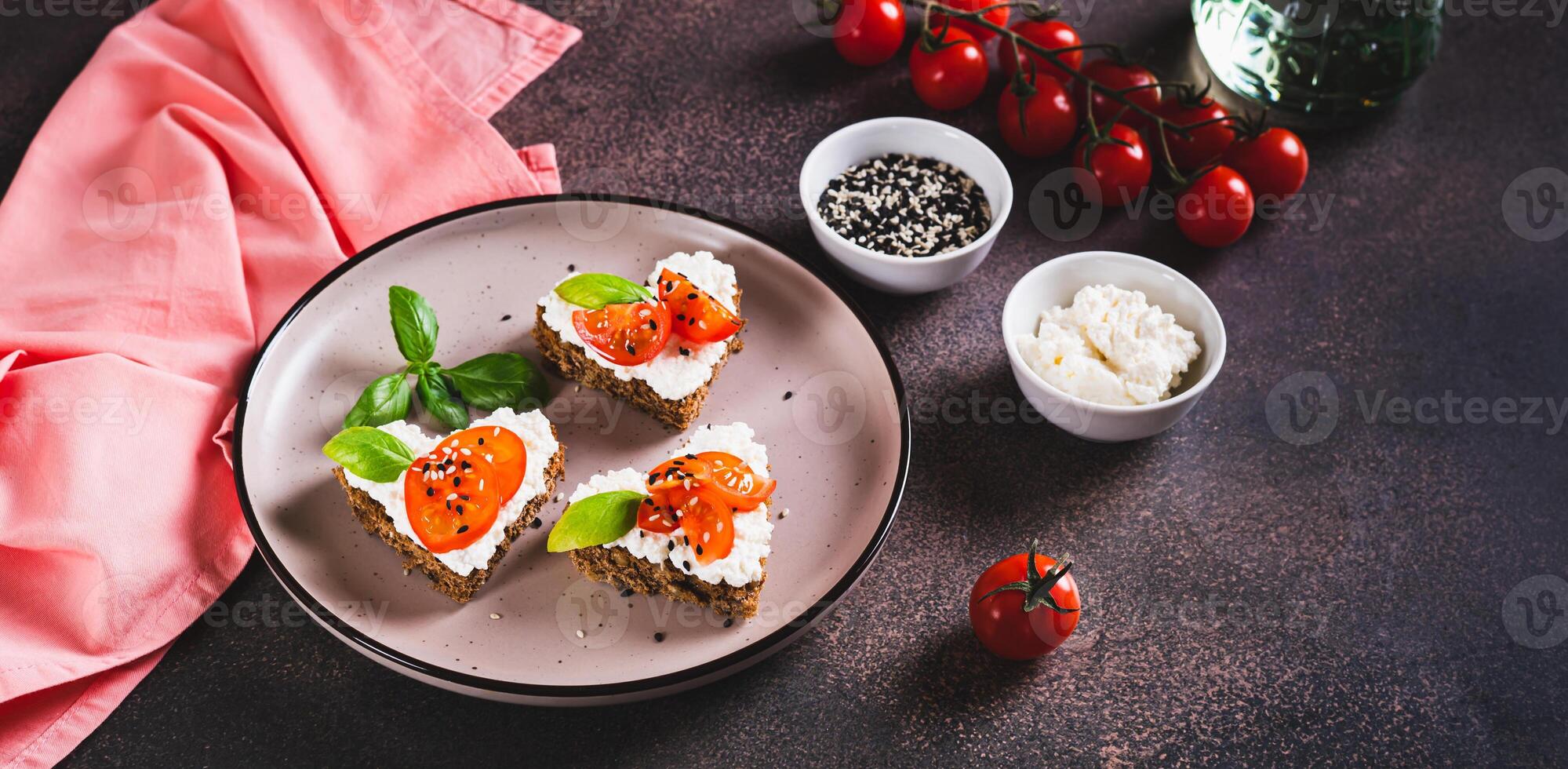Crostini on rye bread in the shape of a heart with ricotta and tomatoes on a plate web banner photo