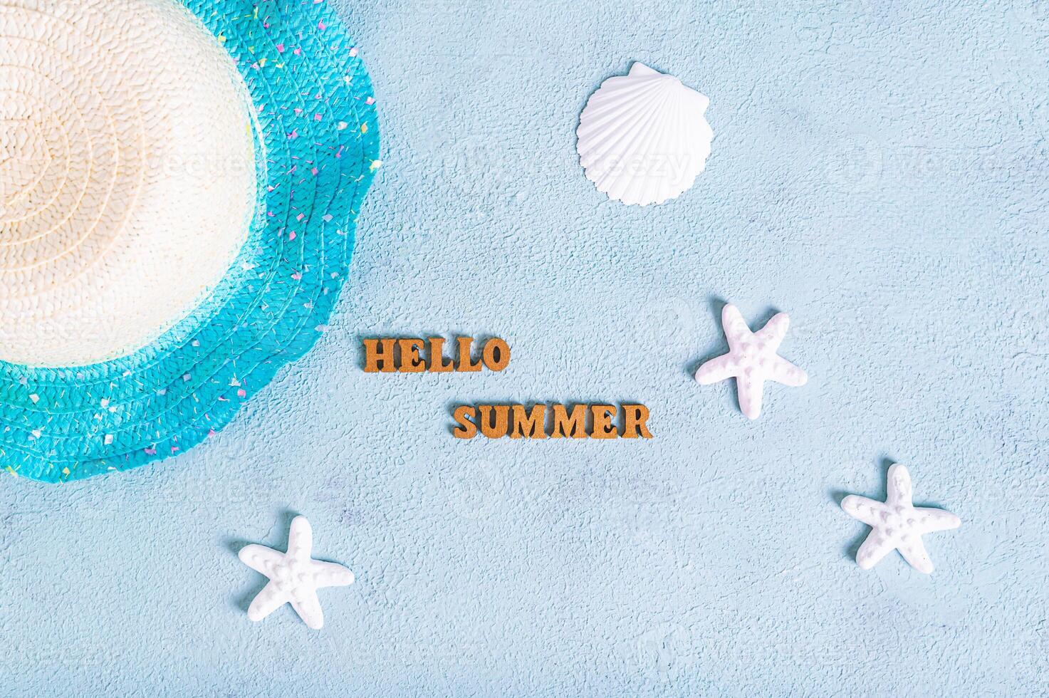Concept hello summer text, hat and starfish on blue background top view photo