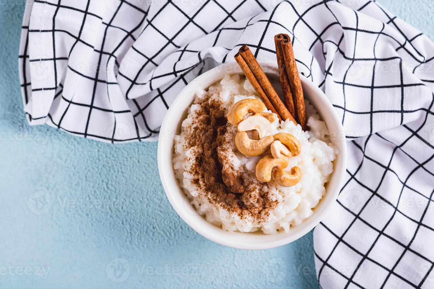 Close up of rice pudding with cinnamon and cashews in a bowl on the table top view photo