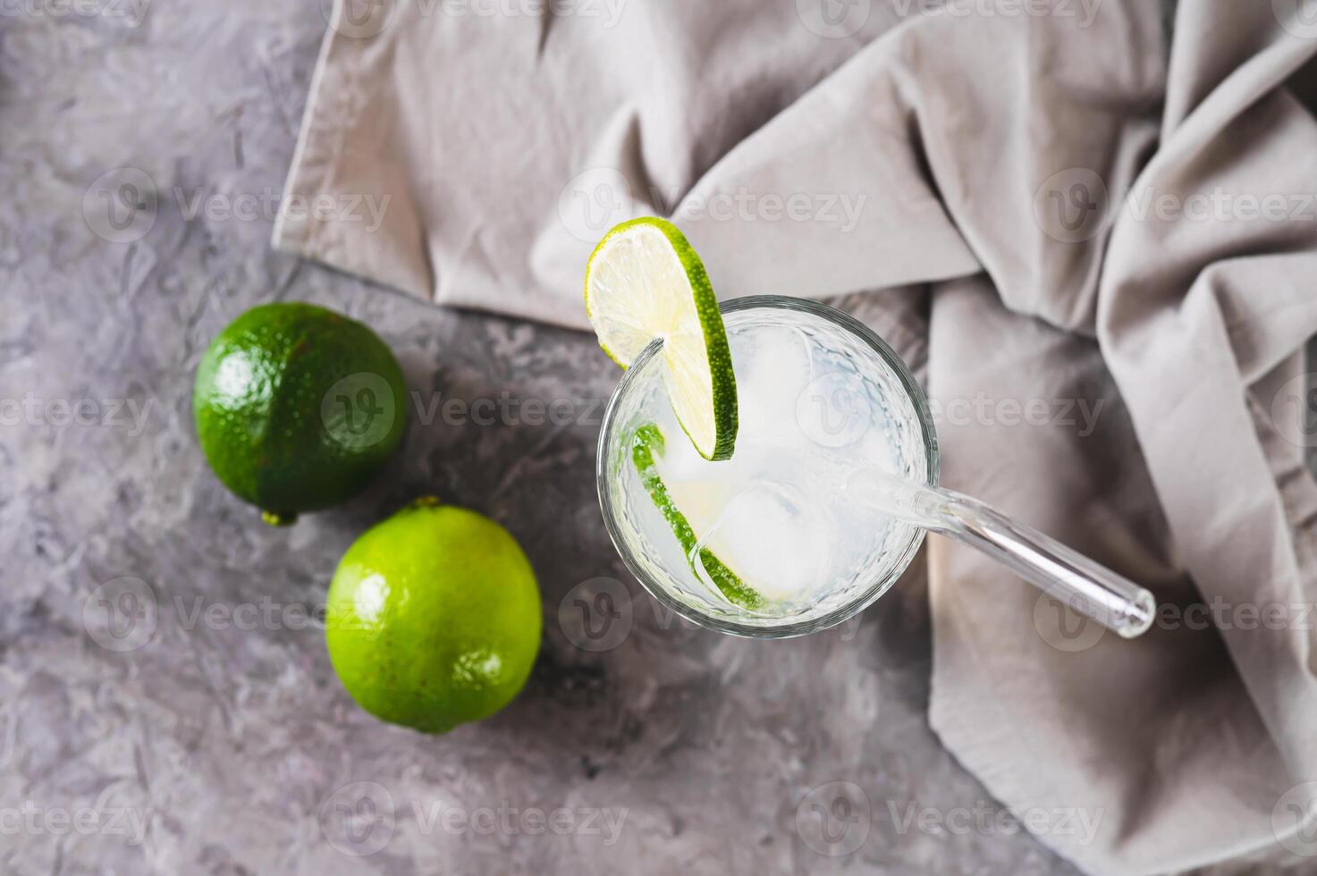Close up of refreshing summer mojito cocktail with ice and lime in a glass on the table top view photo