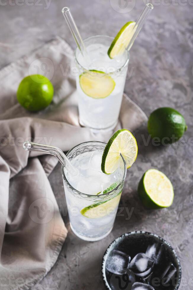 Alcoholic mojito cocktail with lime and ice in glasses on the table vertical view photo