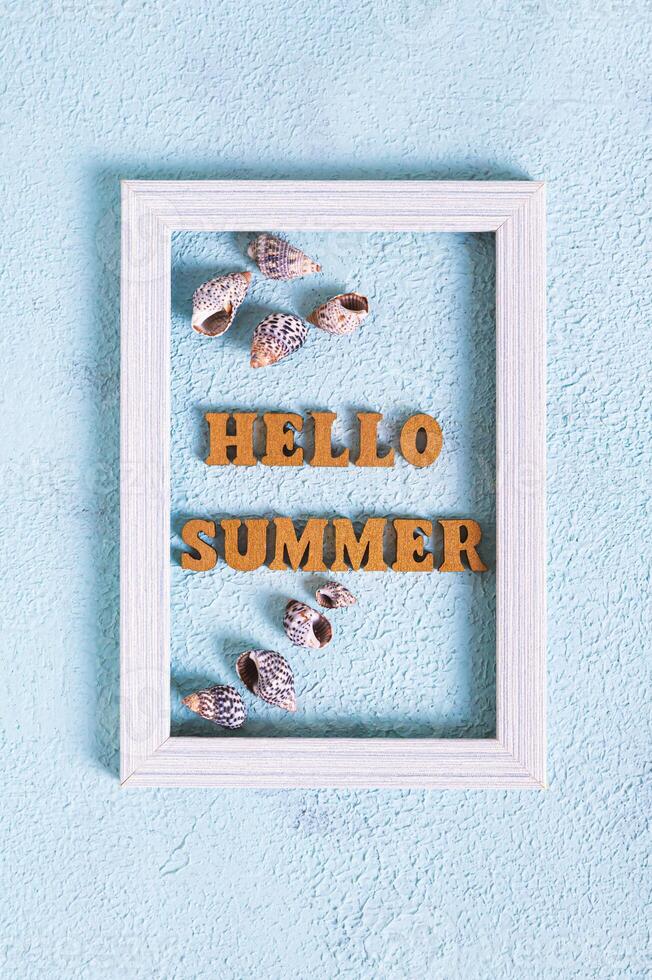 Hello summer text and seashells in photo frame on blue background top view and vertical view