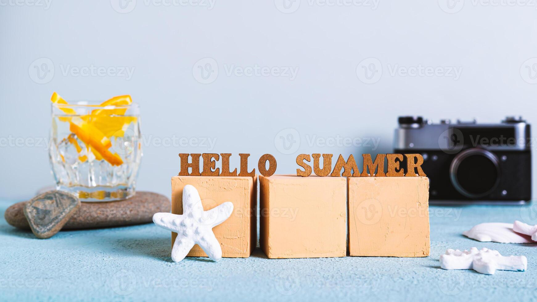 Concept hello summer text on cubes on a background of cocktail, vintage camera and starfish photo