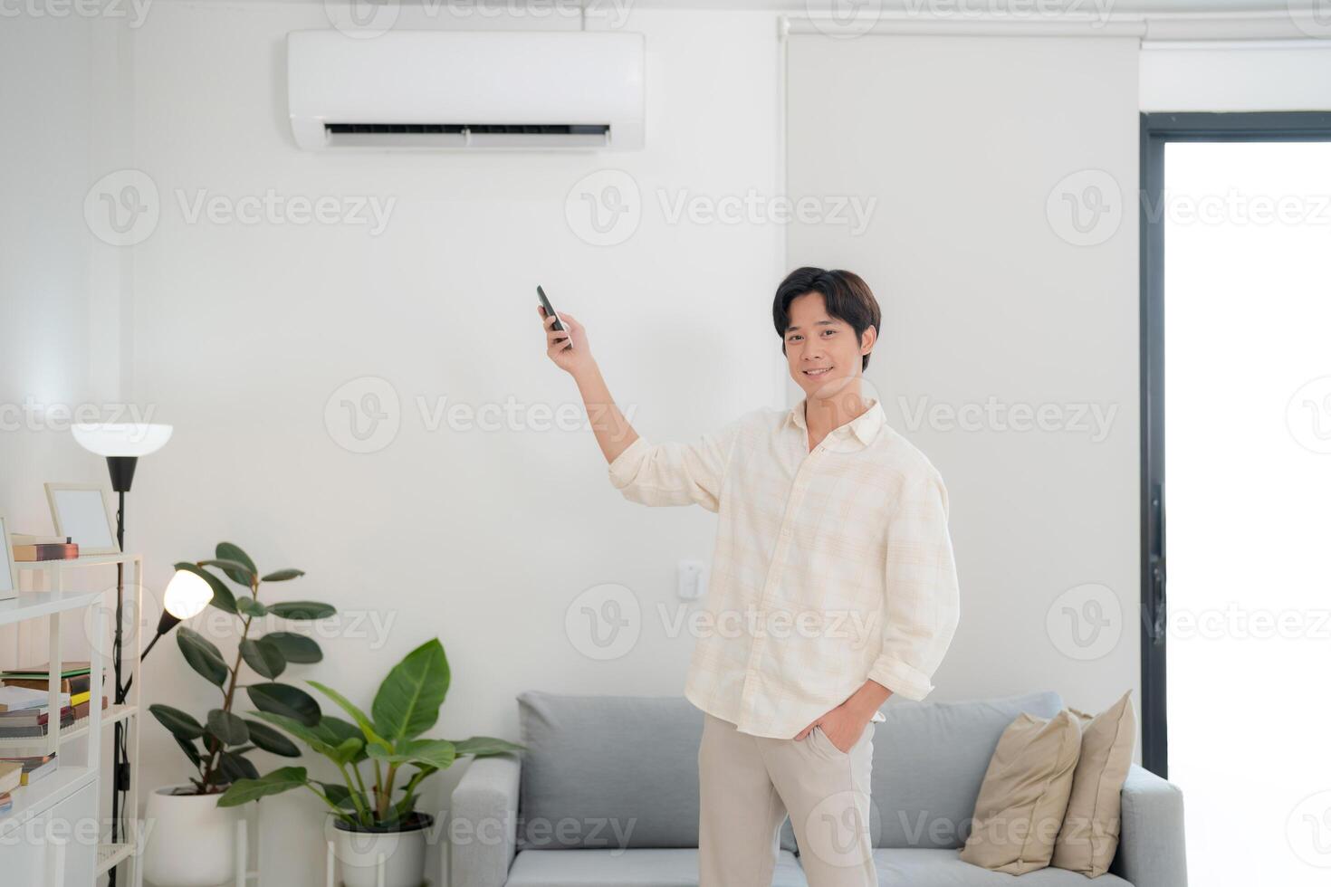 Young man using remote to adjust air conditioning at home photo