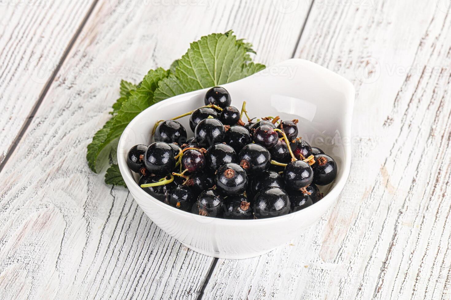Juicy black currant berries in the bowl photo
