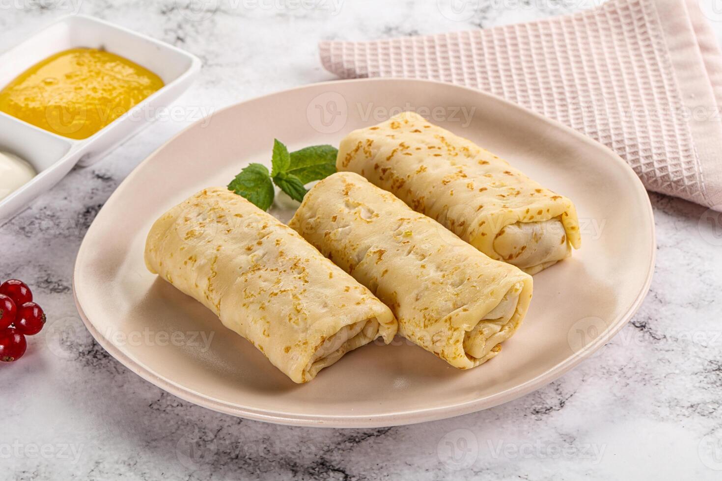 Homemade stuffed pancakes with honey and cream sour photo