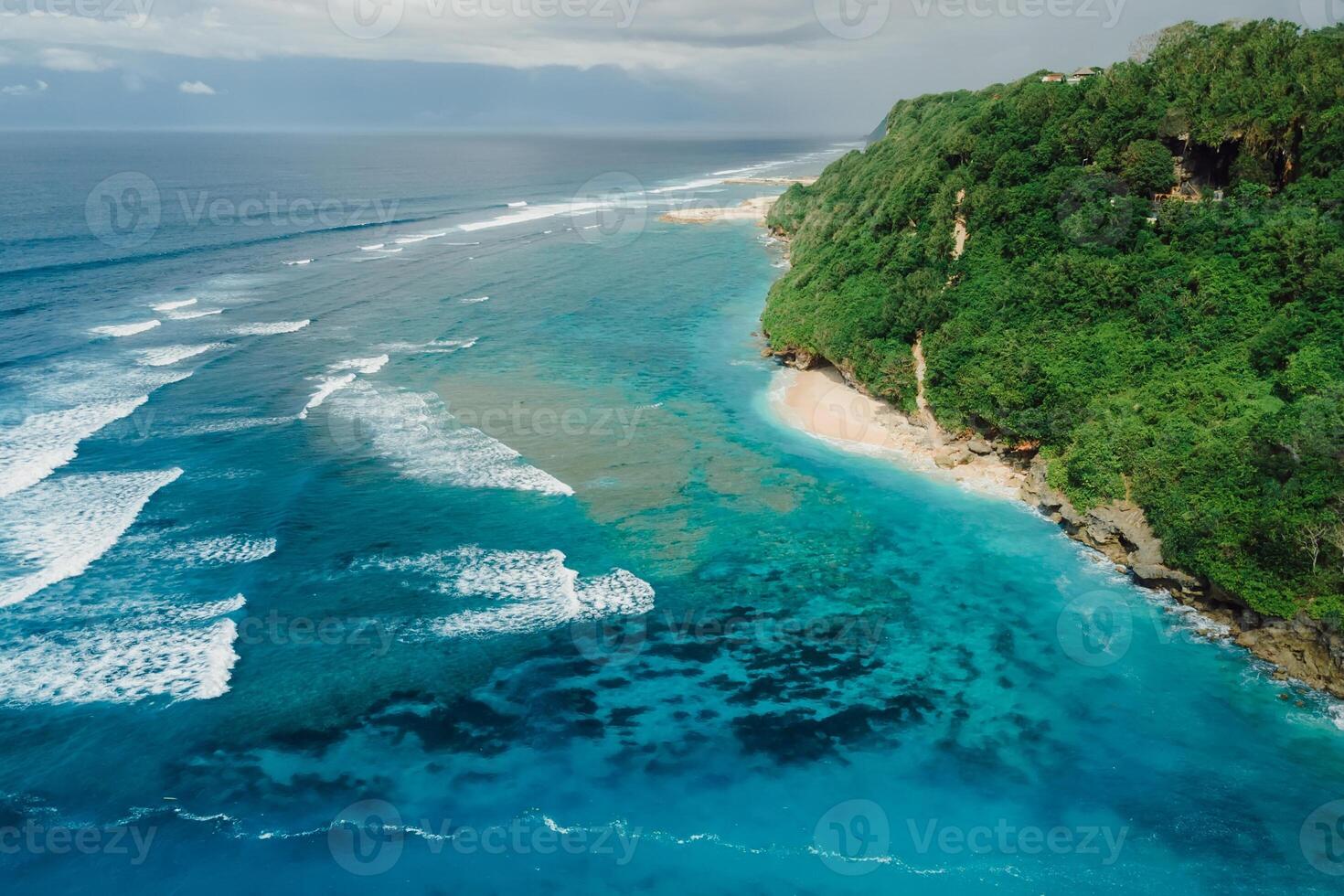 Aerial view of coastline with turquoise ocean and tropical beach under cliffs in Bali. photo