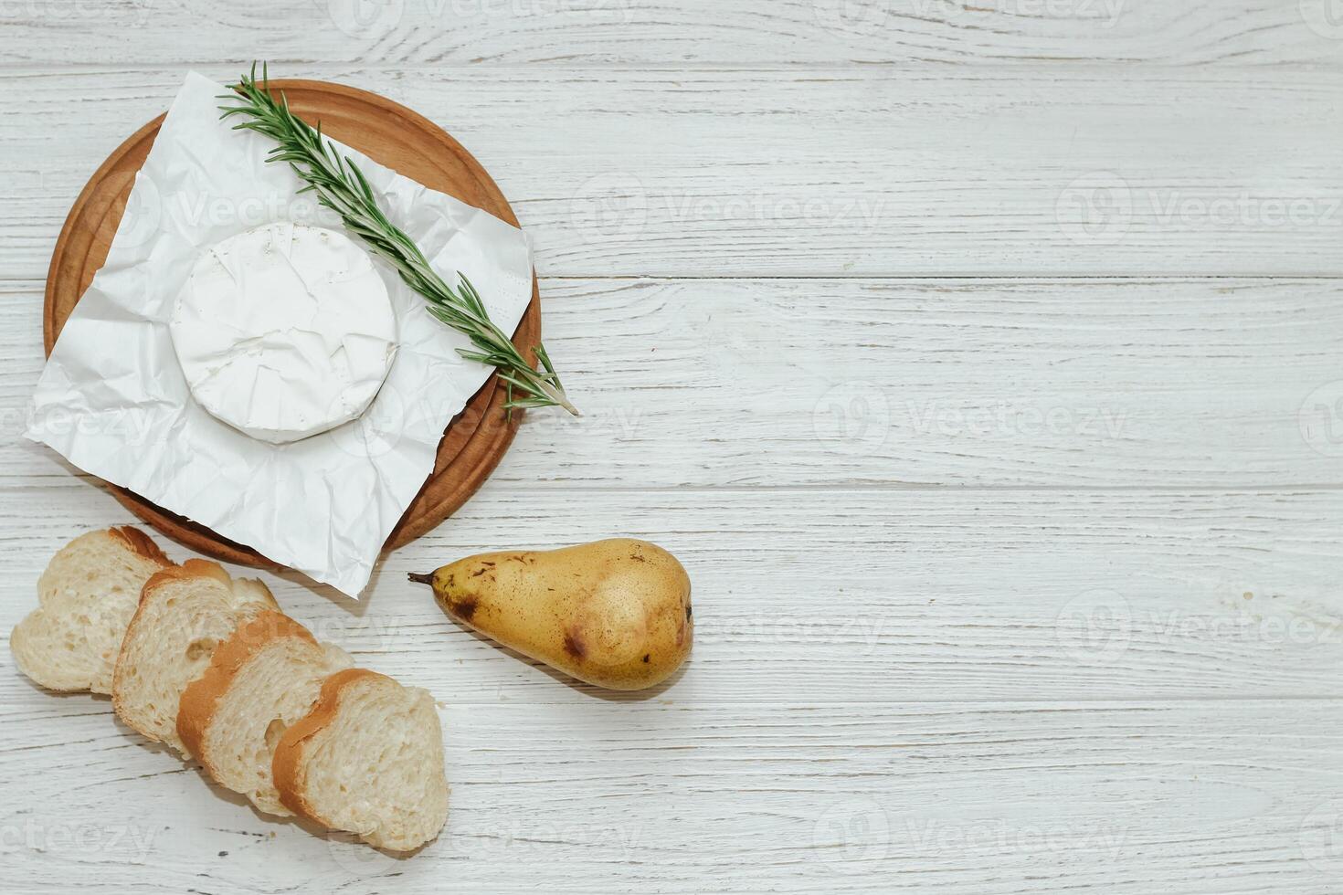 Camembert cheese with pear and rosemary sprig on the table. photo