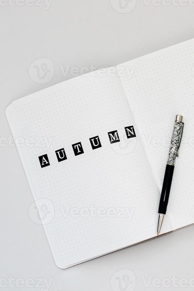 Filling in the diary, writing Autumn in a notebook in a dot photo