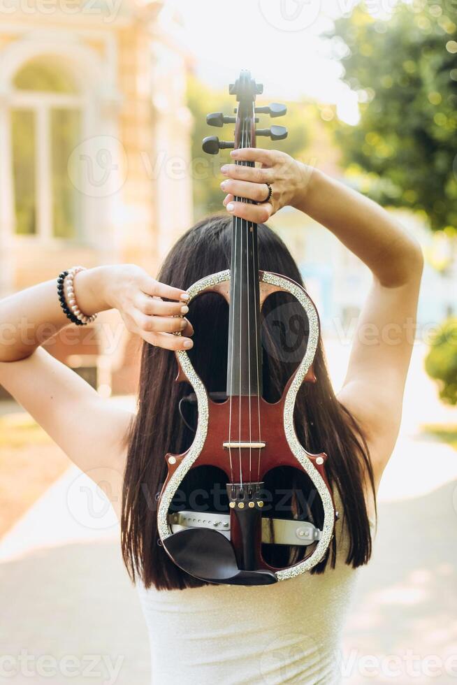 A fragment of an electric violin, a violin in the hands of a musician's girl photo