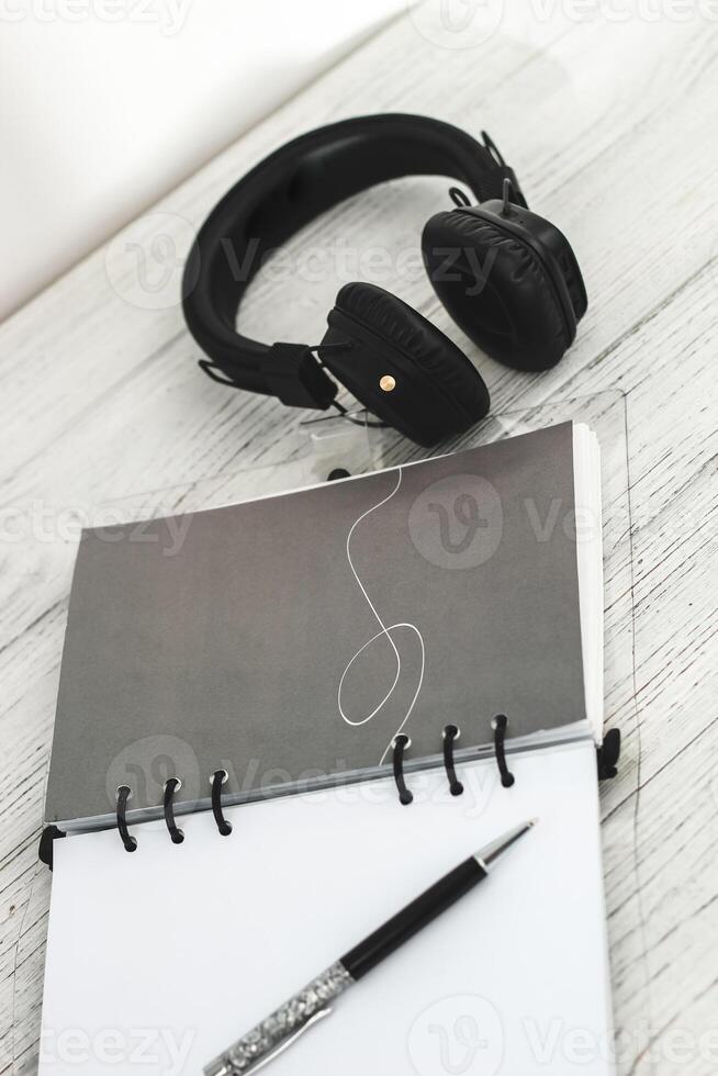 Notepad diary with pen and headphones on the desktop photo