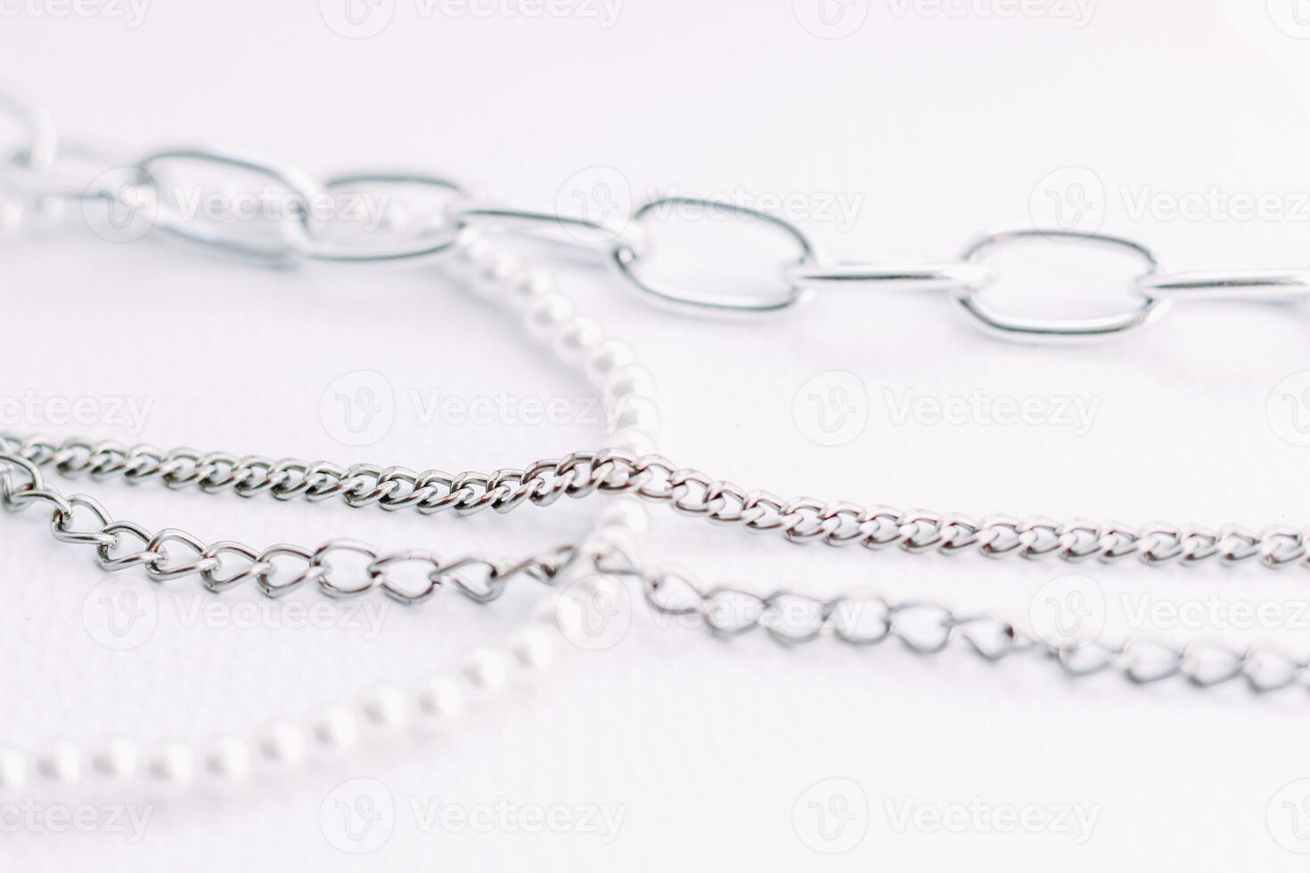 A necklace of white beads with chains of jewelry on a white aesthetic background. photo