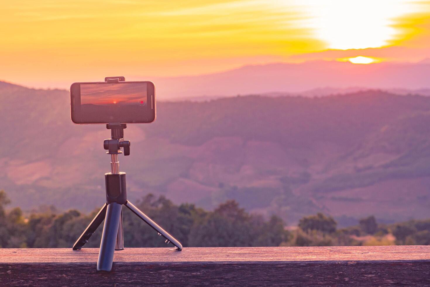 A smartphone is recording the sun setting over a mountain range. photo