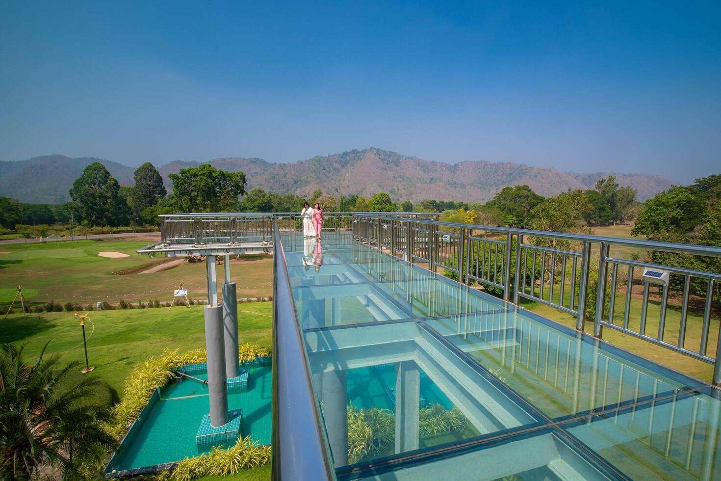 A sky walk at a scene with a mountain, and bridge with a glass floor and stainless steel railing.View from the Vajralongkorn Dam, Kanchanaburi, Thailand. photo