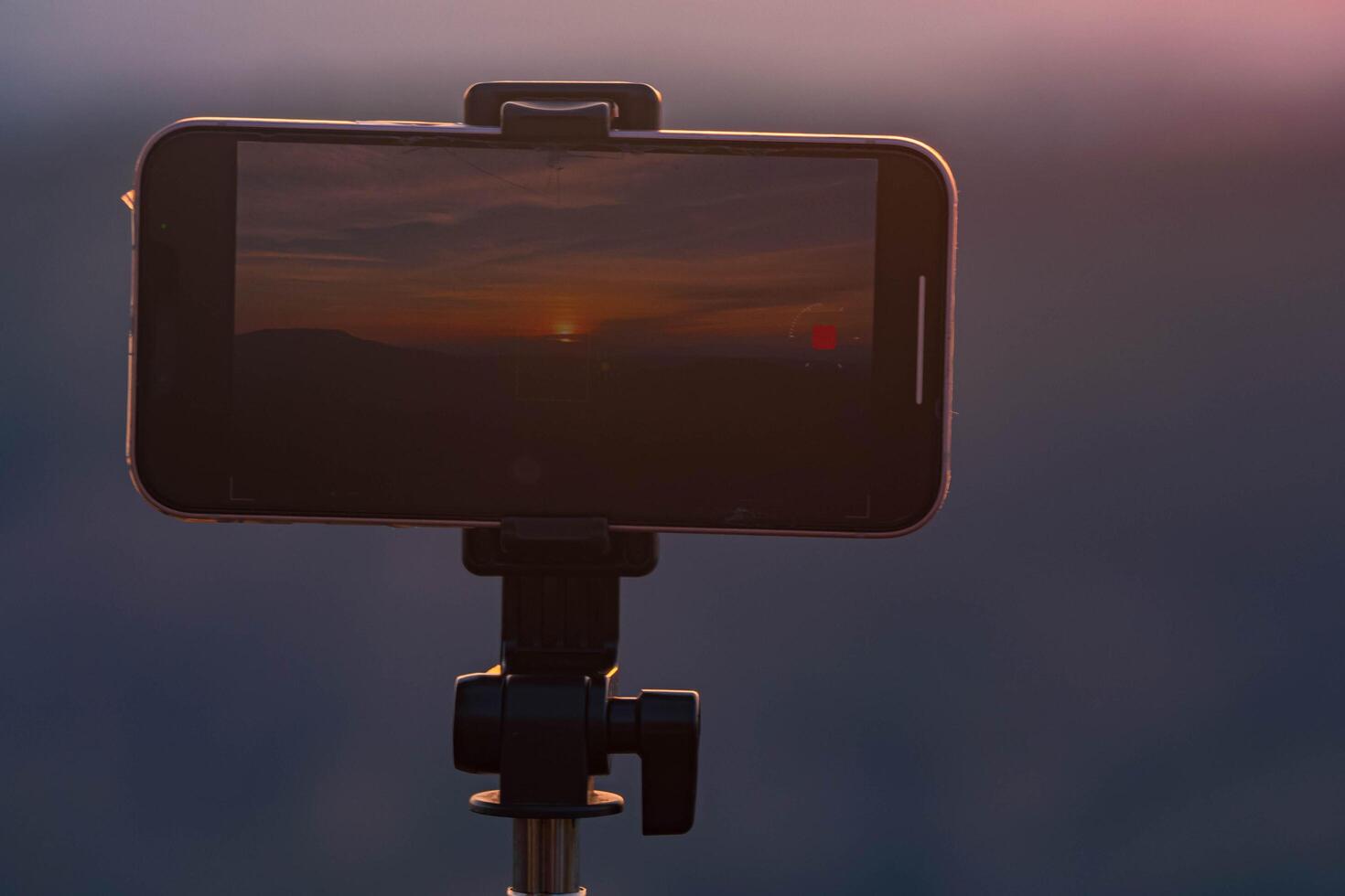 A smartphone is recording the sun setting over a mountain range. photo
