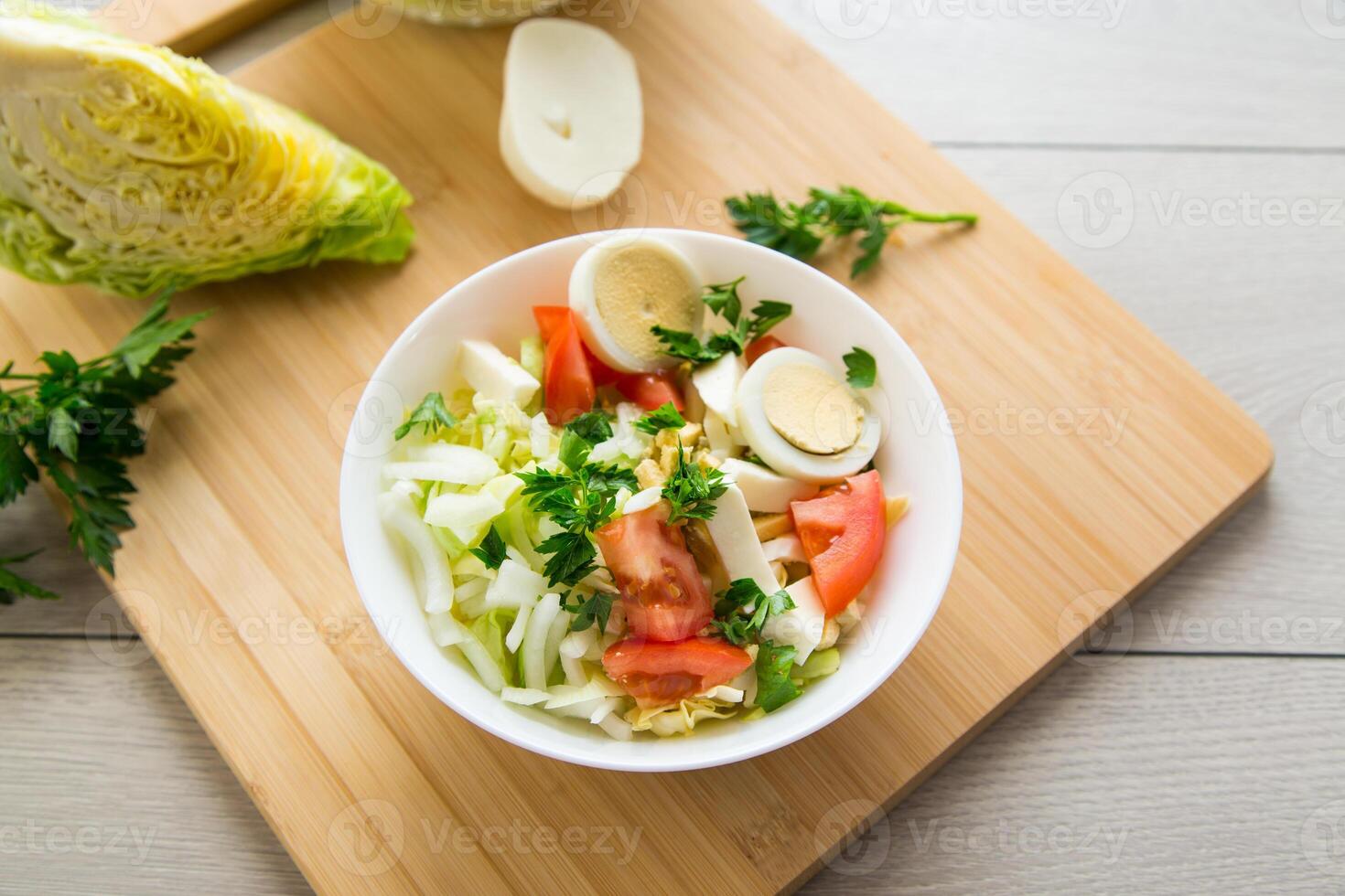 fresh vegetable salad, cabbage, tomatoes in a bowl on a wooden table photo