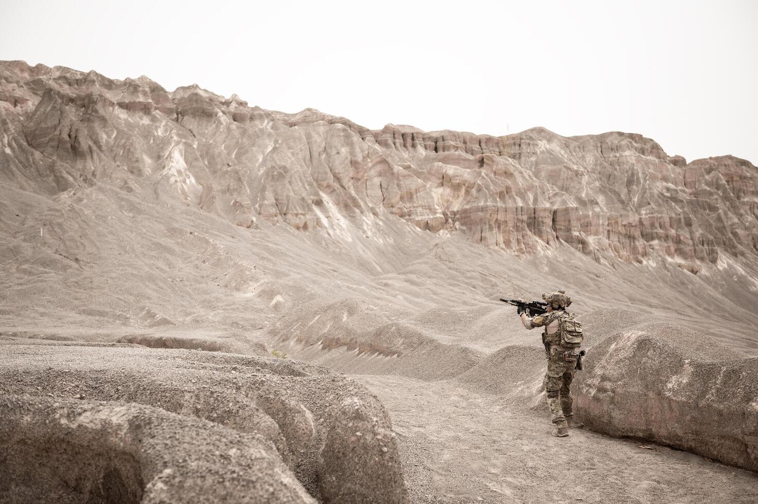 Soldiers in camouflage uniforms aiming with their riflesready to fire during military operation in the desert soldiers training in a military operation photo