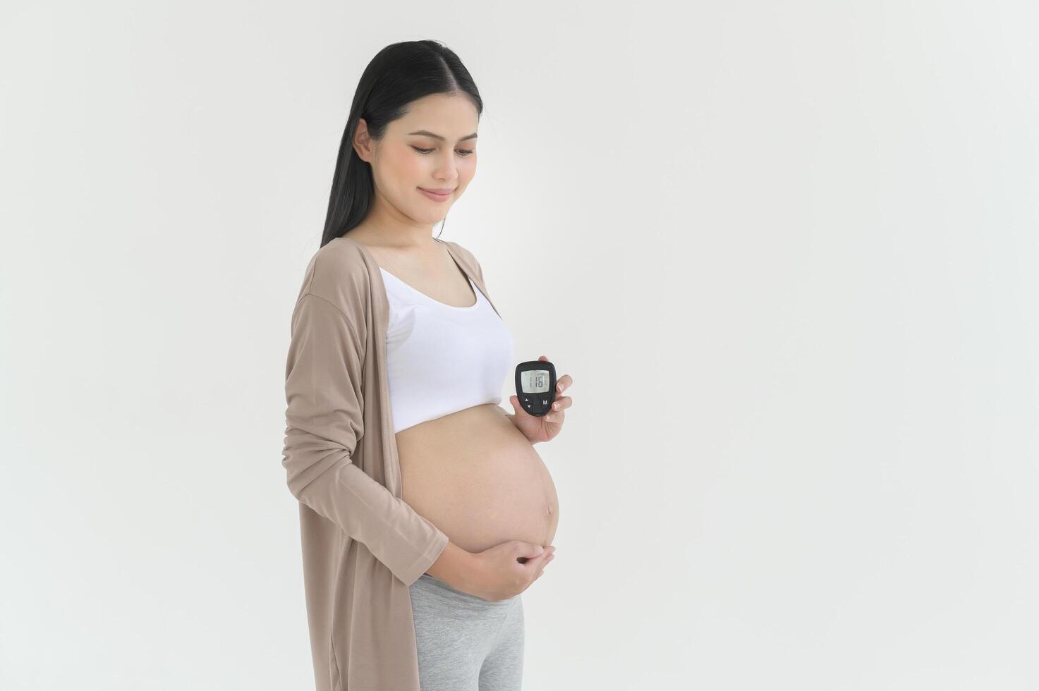 Pregnant woman checking blood sugar level by using Digital Glucose meter, health care, medicine, diabetes, glycemia concept photo