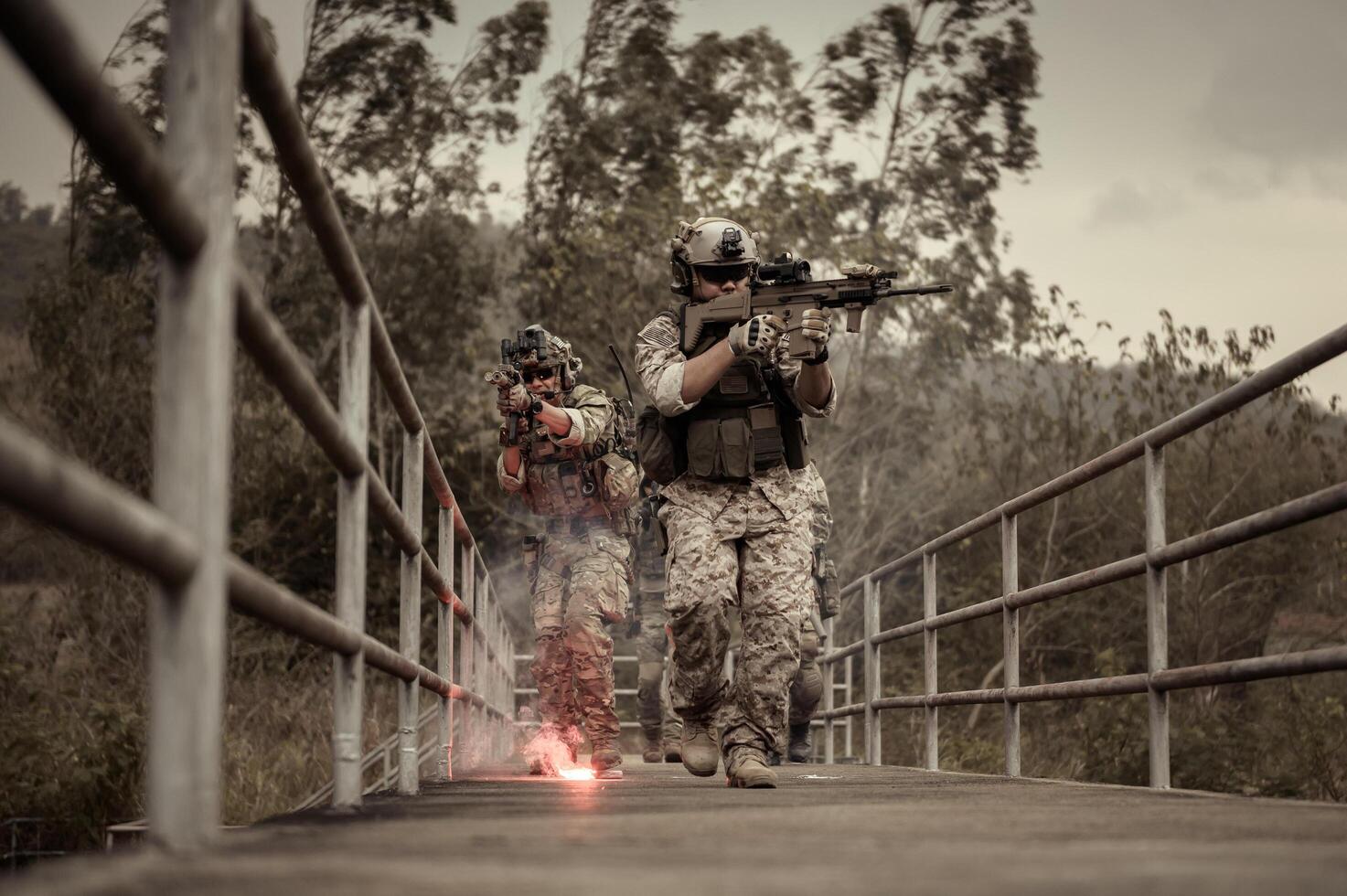Soldiers in camouflage uniforms aiming with their rifles ready to fire during Military Operation in the forest , soldiers training in a military operation photo