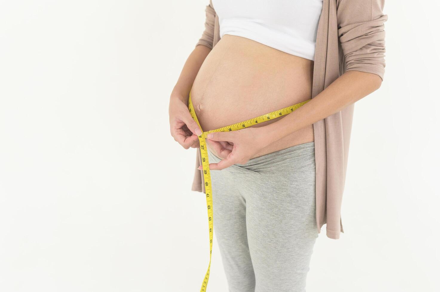 Pregnant woman using measuring tape to check size of belly pregnancy and baby development photo