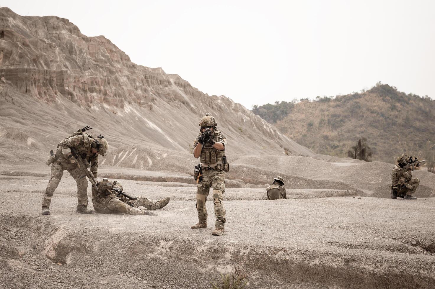 Soldiers in camouflage uniforms aiming with their rifles ready to fire during military operation in the desert , soldiers training in a military operation photo