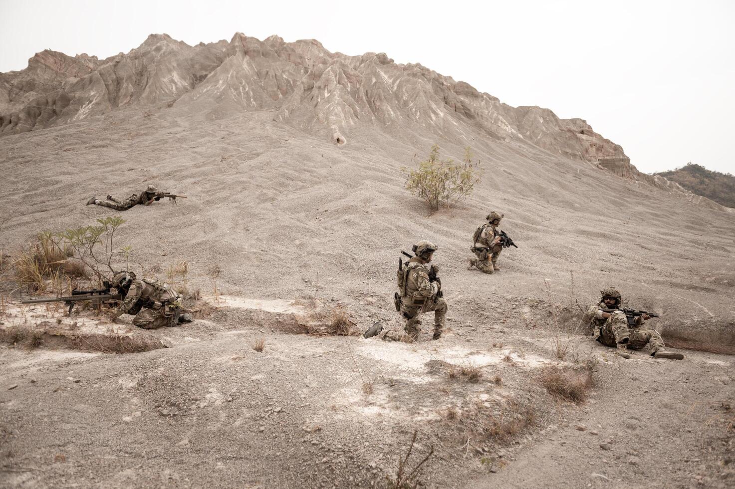 Soldiers in camouflage uniforms aiming with their rifles ready to fire during military operation in the desert , soldiers training in a military operation photo