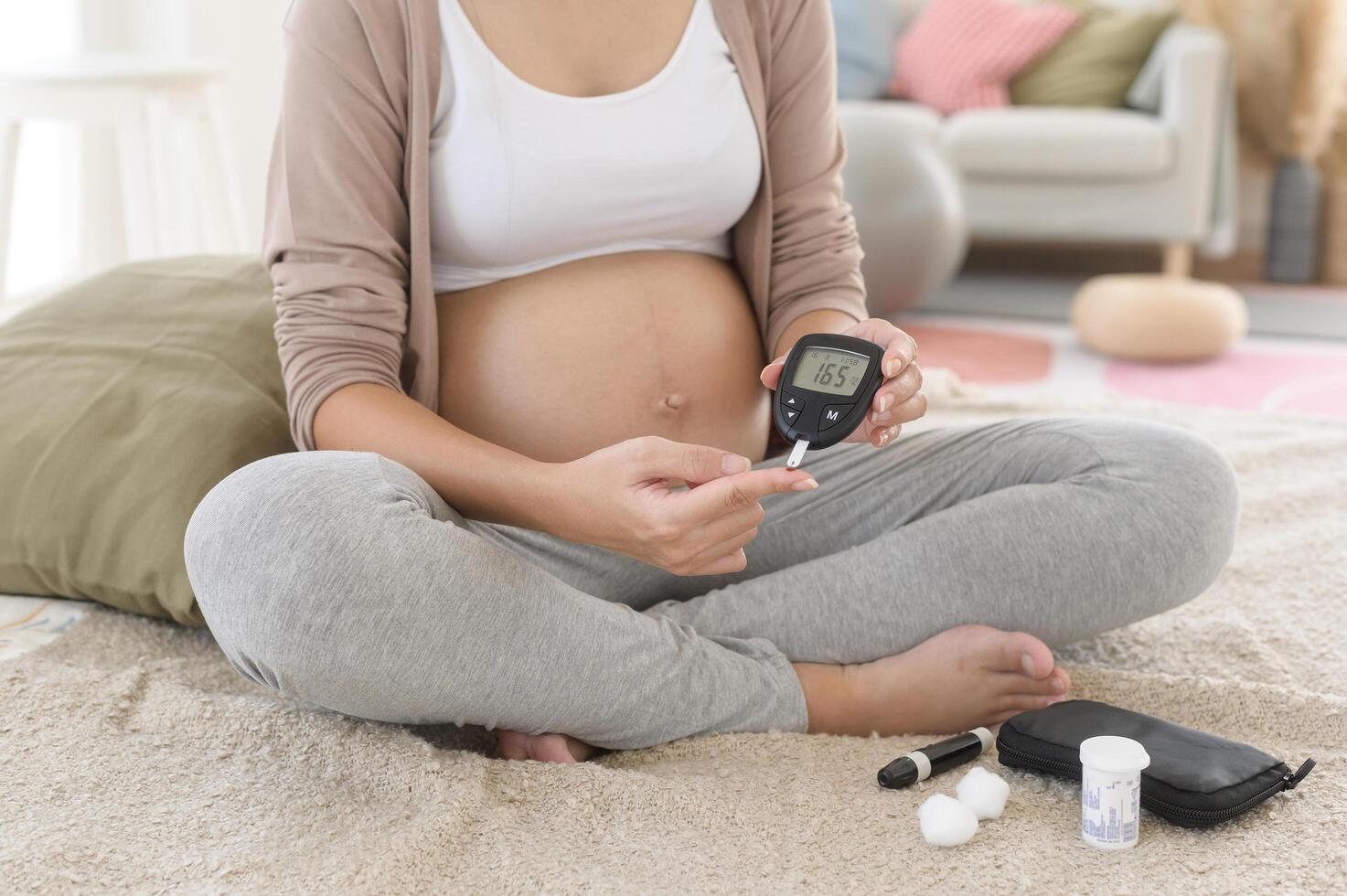 Pregnant woman checking blood sugar level by using Digital Glucose meter, health care, medicine, diabetes, glycemia concept photo