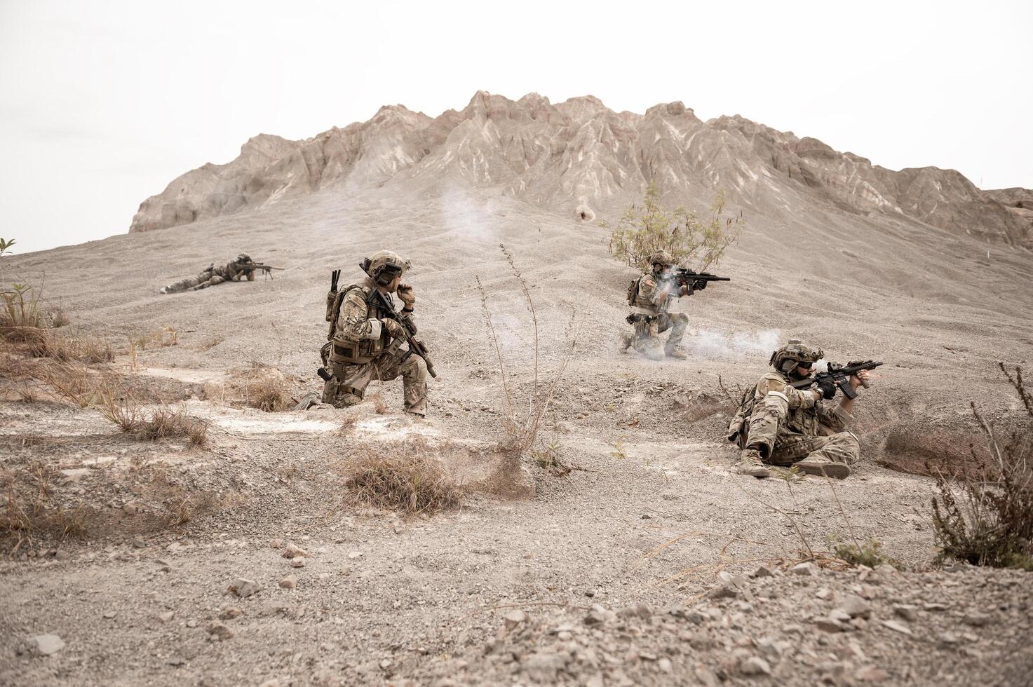 Soldiers in camouflage uniforms aiming with their rifles ready to fire during military operation in the desert soldiers training in a military operation photo