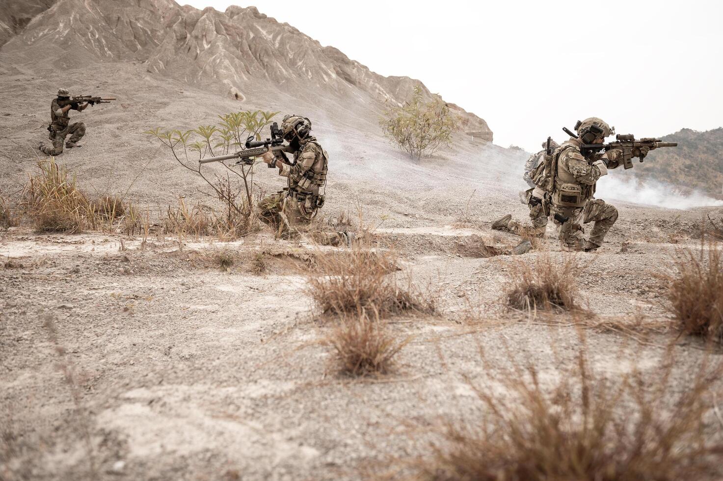 Soldiers in camouflage uniforms aiming with their rifles ready to fire during military operation in the desert , soldiers training in a military operation photo