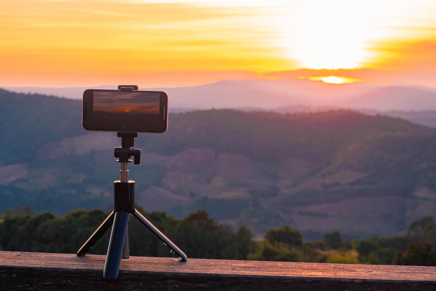 A smartphone is recording the sun setting over a mountain range. photo