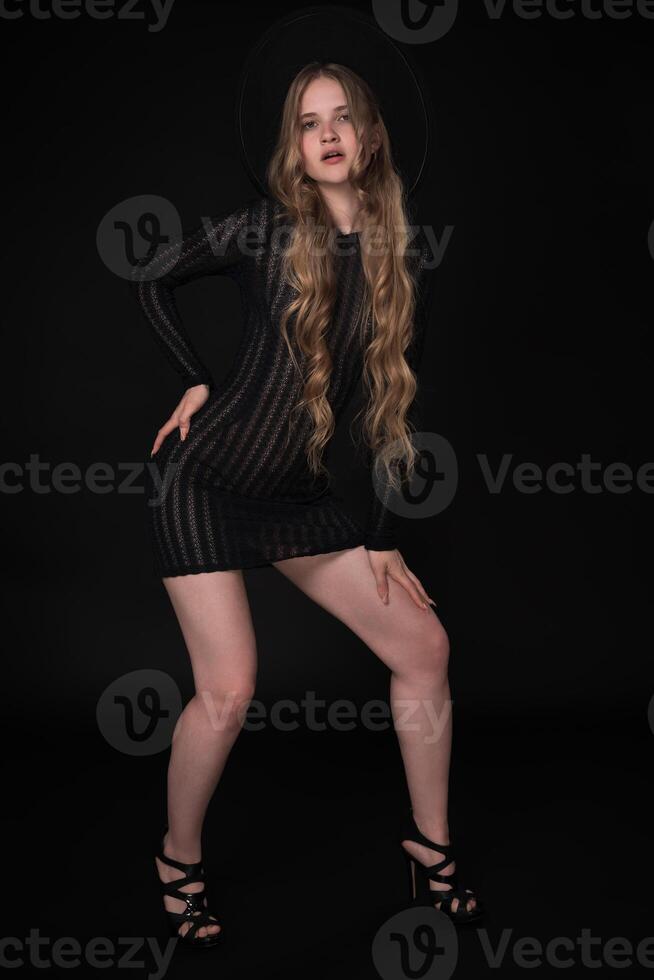 Full length portrait of a young woman, 21 years old, with long legs, posing against black background photo