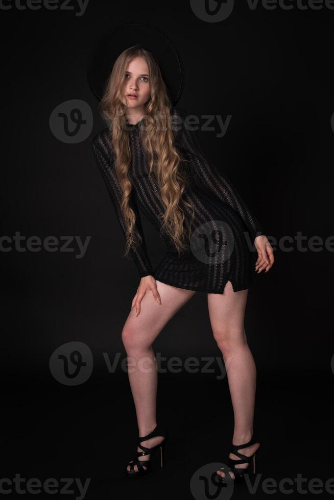 Full length portrait of sexy blonde young woman with long legs on black background photo