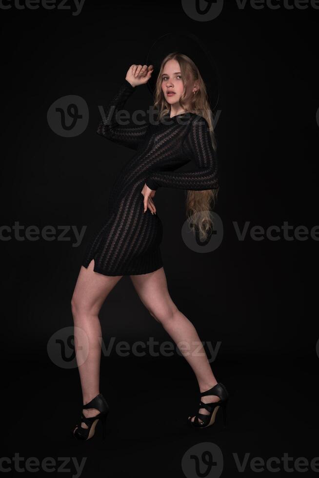 Full length portrait of 21 year old Caucasian woman is posing in front of black background photo