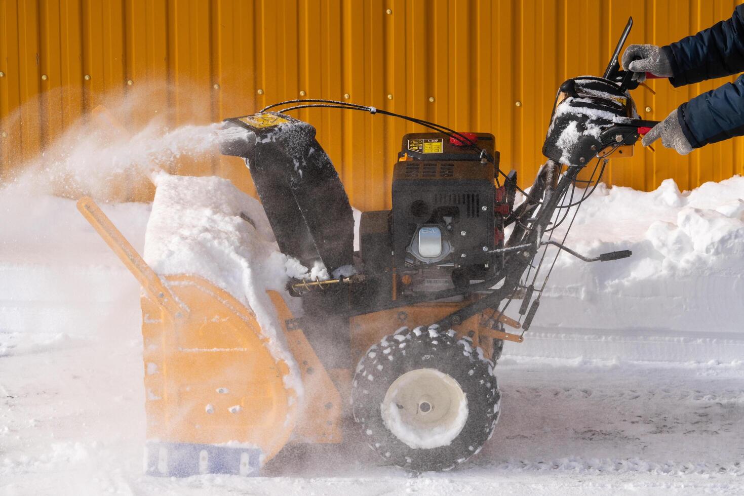 Man using snowblower to remove snow after winter storm. He is assisted by a snow thrower on a winter road photo