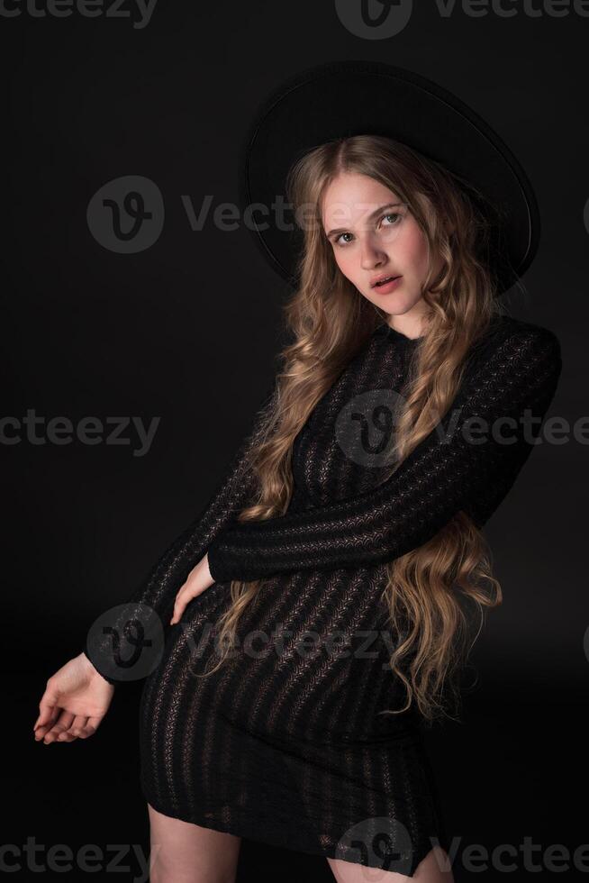 Portrait of blonde model exuding sensuality in relaxed pose on black background, looking at camera photo