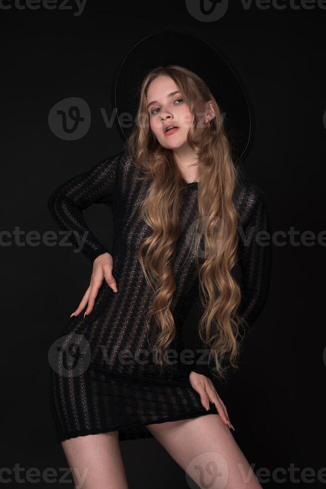 Blonde with long hair and gorgeous features are accentuated by black background, she looks amazing photo