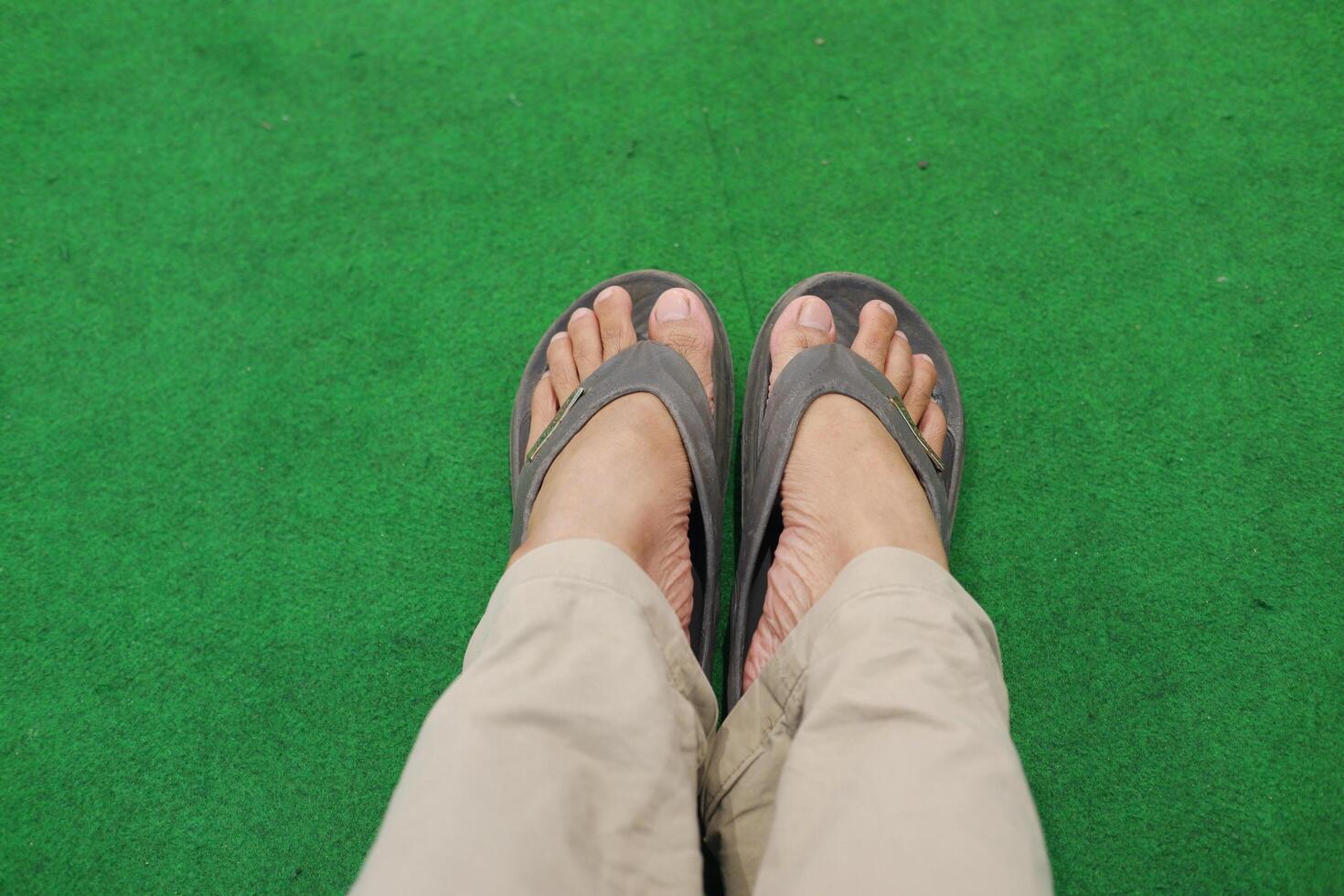 male feet in sandals on a green carpet. Close-up. photo