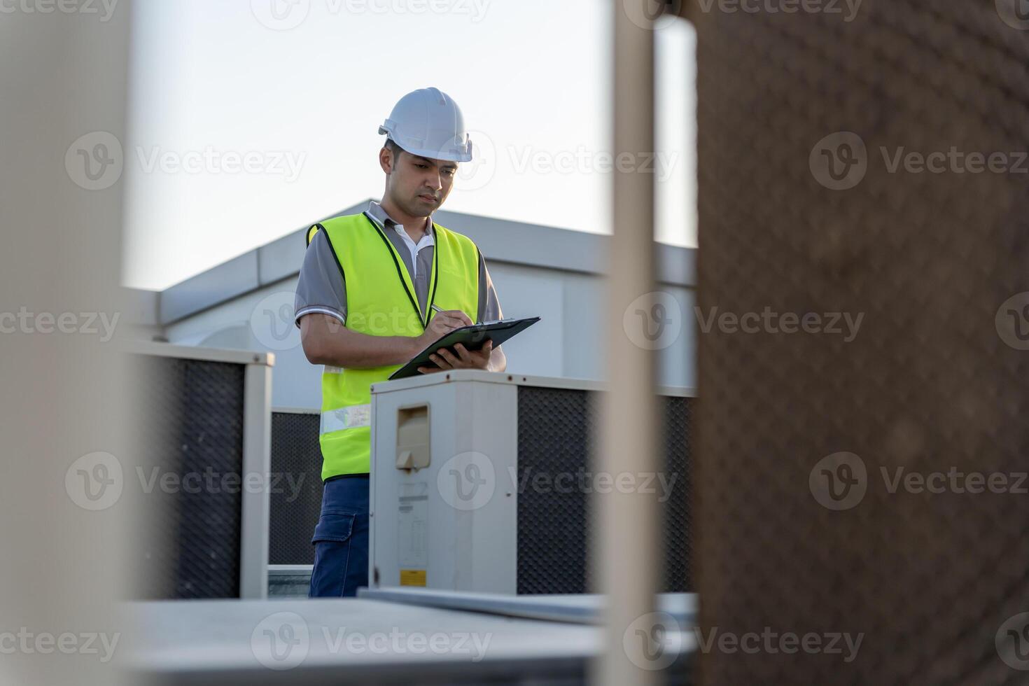 Asian maintenance engineer works on the roof of factory. contractor inspect compressor system and plans installation of air condition systems in construction. Checklist, inspector, control photo
