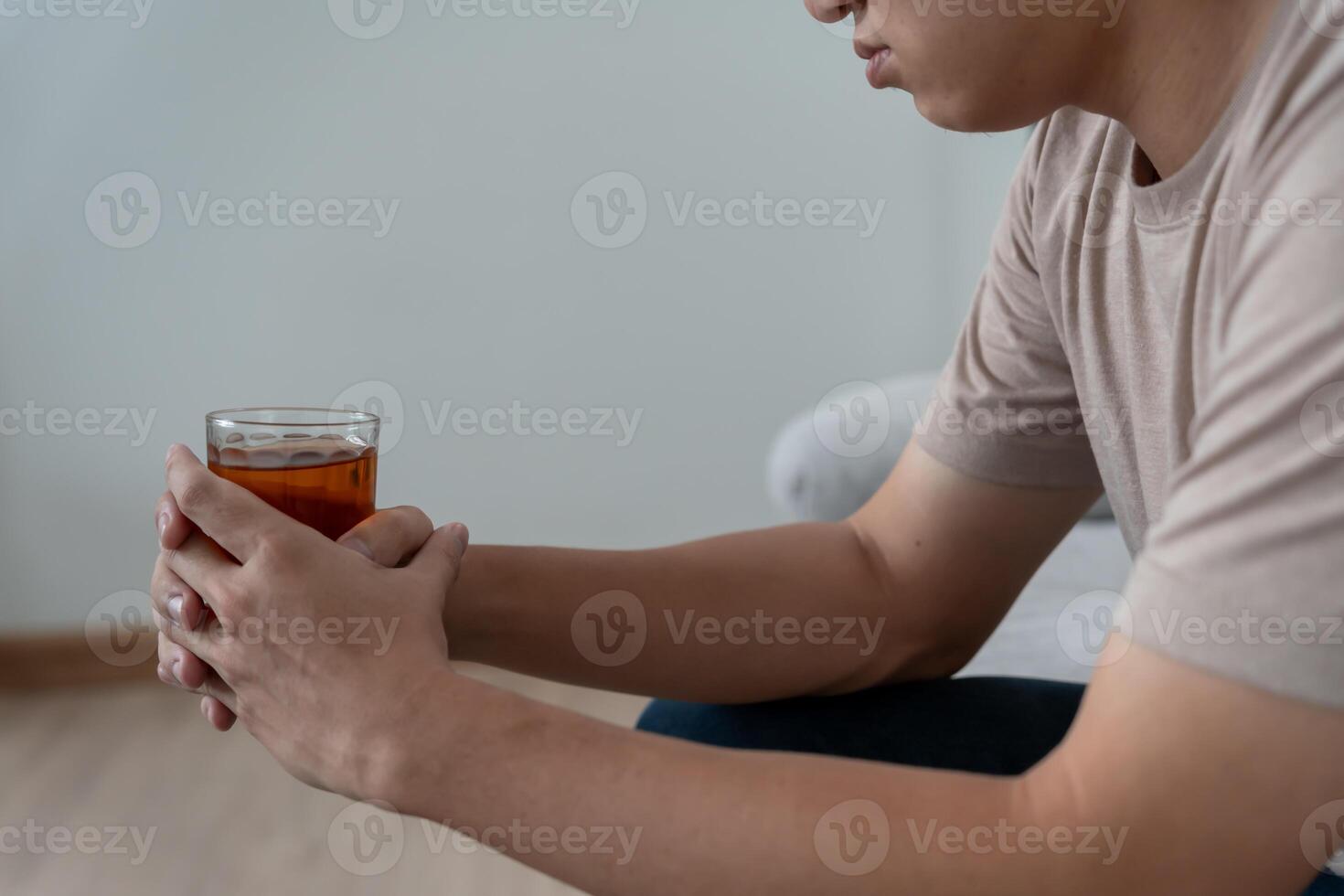 Depressed young Asian man addicted feeling bad drinking whiskey alone at home, stressed frustrated lonely drinking alcohol suffers from problematic liquor, alcoholism, life and family problems photo
